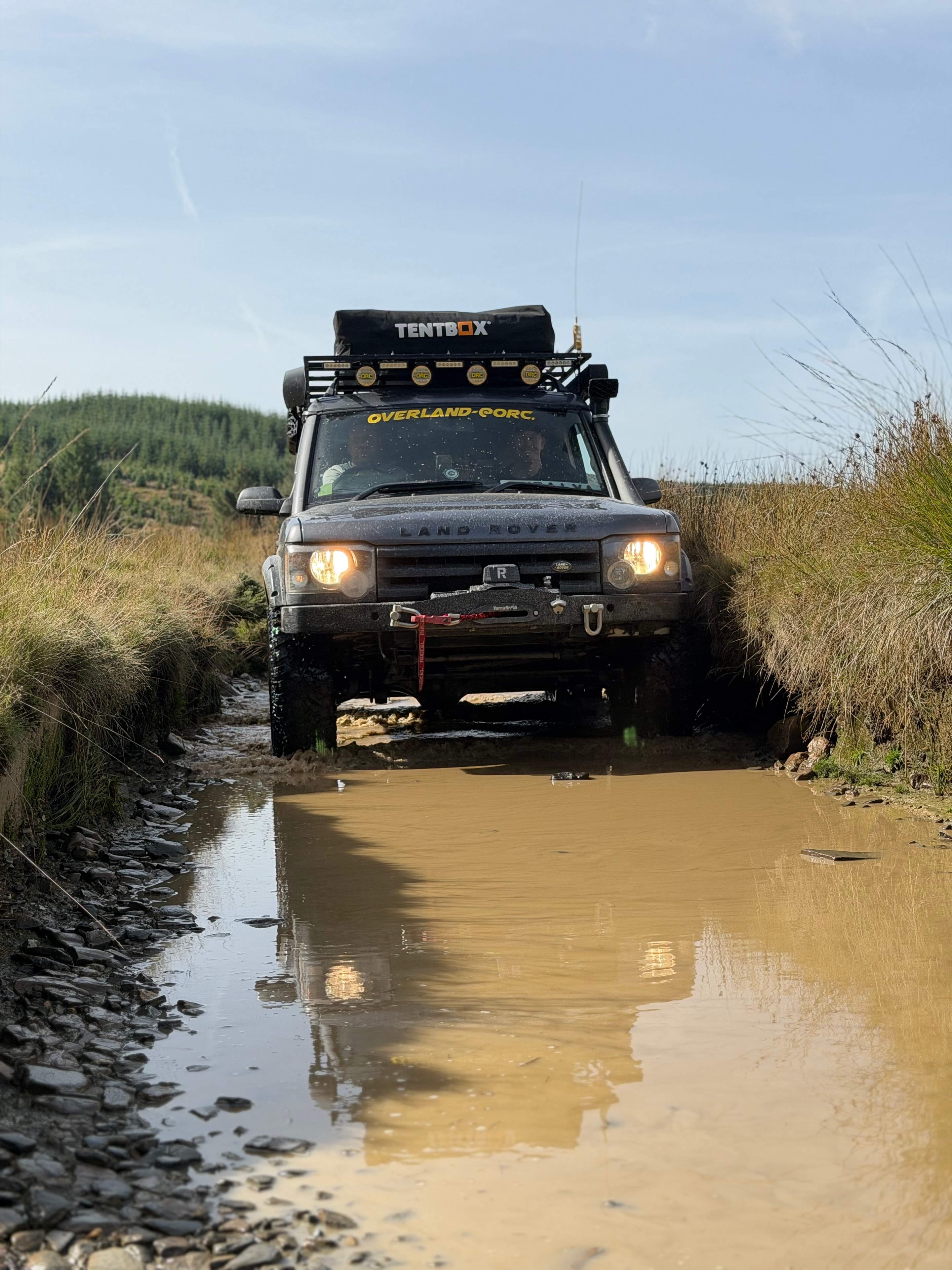Land Rover powering through a muddy puddle on B@stard Lane